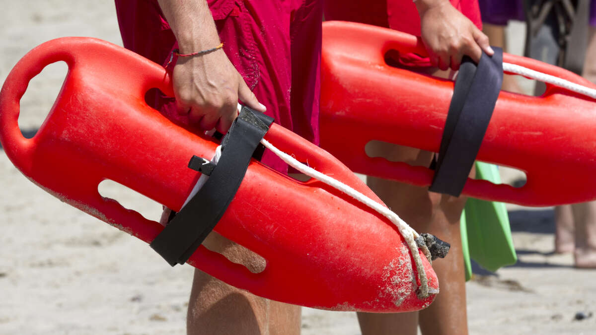 Two lifeguards holding their rescue buoys. .