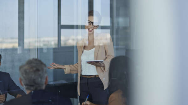 Business people dressed casual/corporate, talking together in large glass conference room